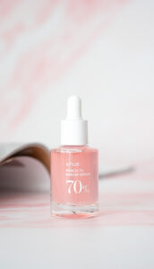 A 30mL Bottle of Anua Peach 70 Niacin Serum on a pink marble background