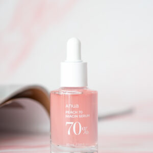 A 30mL Bottle of Anua Peach 70 Niacin Serum on a pink marble background